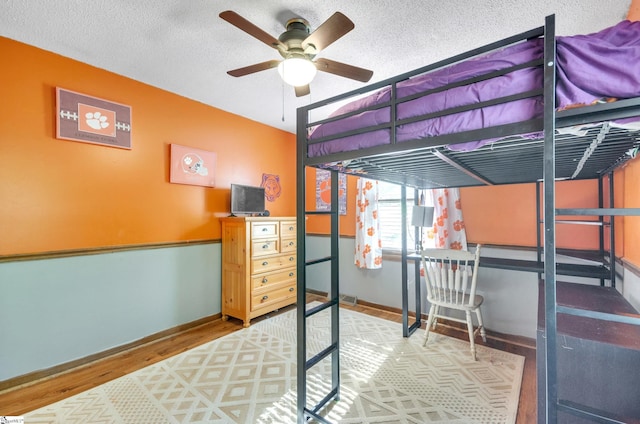 bedroom featuring hardwood / wood-style floors, a textured ceiling, and ceiling fan