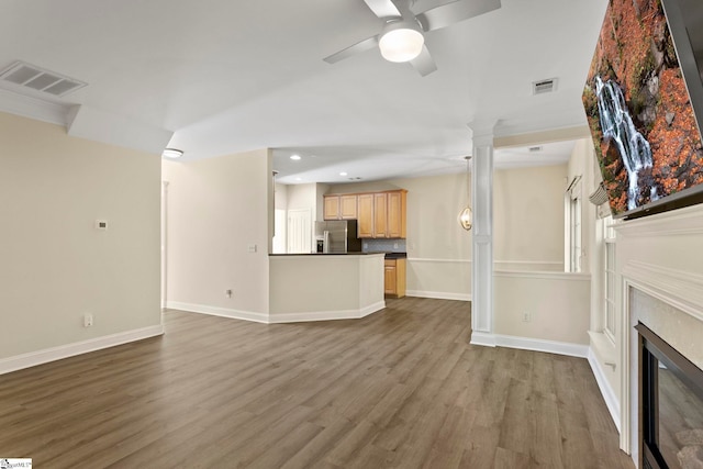 unfurnished living room with ornate columns, hardwood / wood-style flooring, and ceiling fan