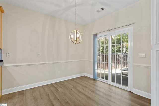 unfurnished dining area featuring hardwood / wood-style flooring and a chandelier