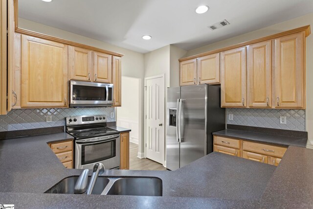 kitchen featuring light hardwood / wood-style flooring, stainless steel appliances, decorative backsplash, and sink