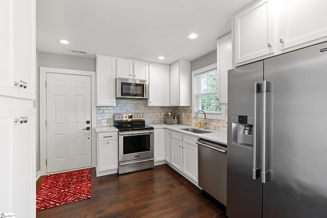 kitchen featuring white cabinets, tasteful backsplash, dark wood-type flooring, sink, and stainless steel appliances