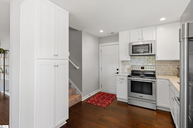 kitchen with backsplash, white cabinetry, stainless steel appliances, and dark hardwood / wood-style floors