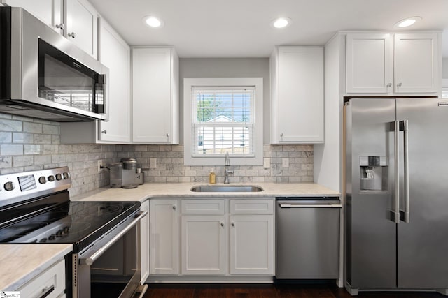 kitchen with white cabinetry, stainless steel appliances, tasteful backsplash, and sink