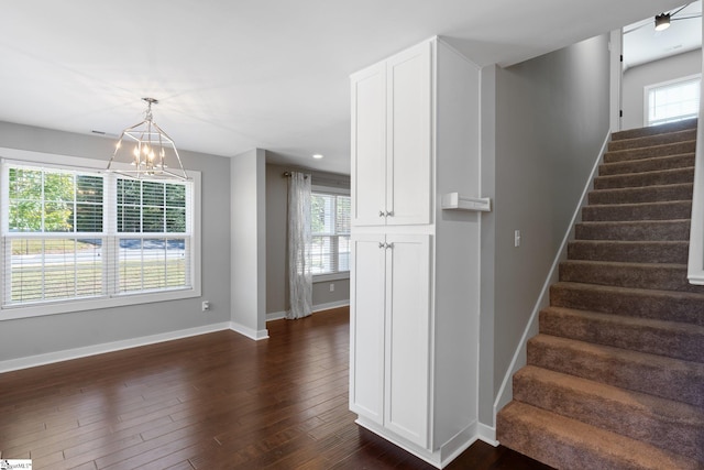 stairs featuring a notable chandelier and wood-type flooring