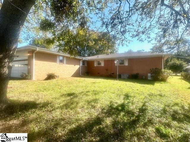 back of house with a garage and a lawn