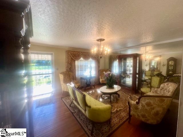 living room with a wealth of natural light, crown molding, hardwood / wood-style flooring, and a notable chandelier