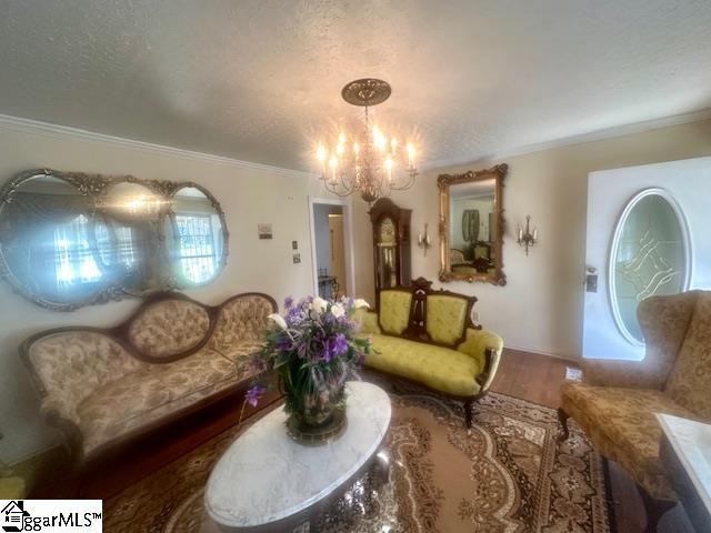 sitting room featuring a notable chandelier, ornamental molding, and a textured ceiling