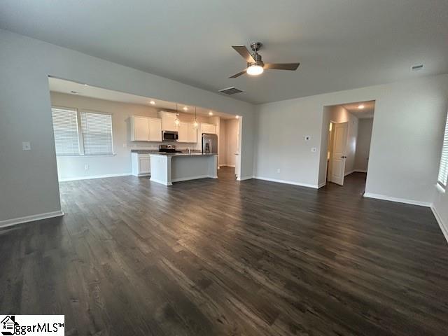 unfurnished living room with dark hardwood / wood-style flooring and ceiling fan