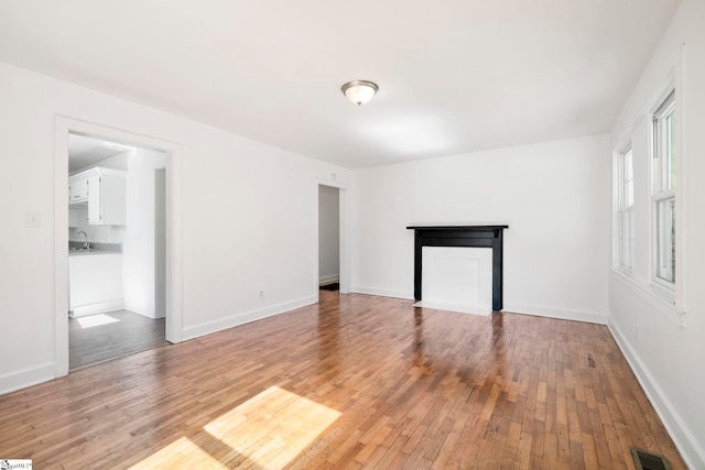 unfurnished living room with light hardwood / wood-style floors and sink