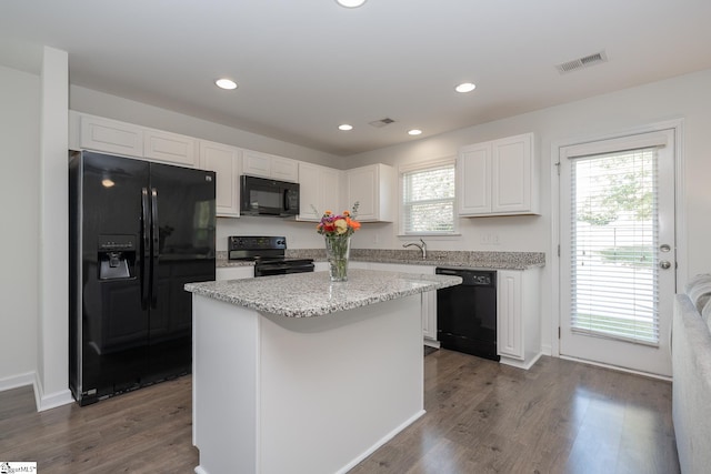 kitchen with a wealth of natural light, black appliances, white cabinetry, and a kitchen island