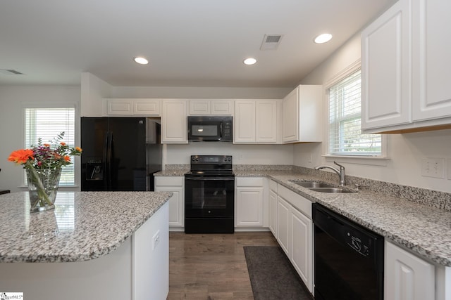 kitchen with dark wood-type flooring, sink, black appliances, white cabinets, and light stone counters