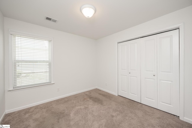 unfurnished bedroom featuring light carpet and a closet