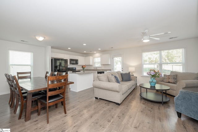 living room with ceiling fan, sink, and light wood-type flooring