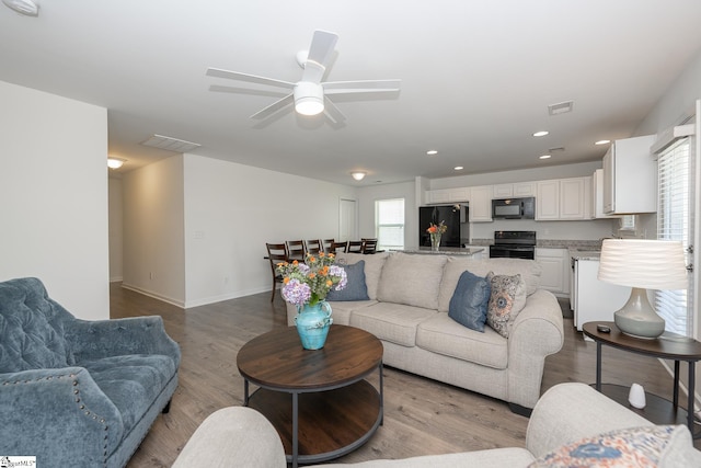 living room featuring ceiling fan, plenty of natural light, and light wood-type flooring