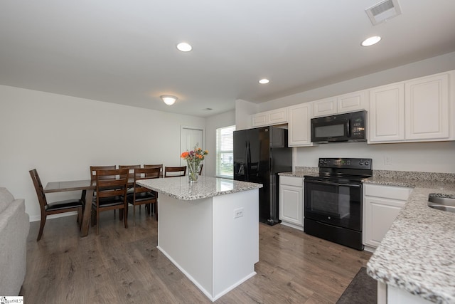 kitchen with a center island, white cabinetry, black appliances, and wood-type flooring