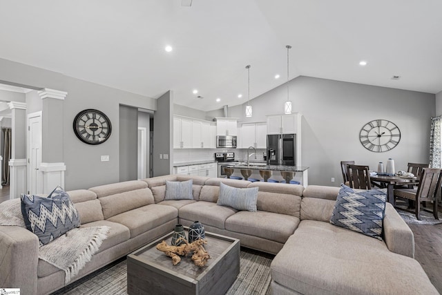 living room featuring decorative columns, lofted ceiling, sink, and dark hardwood / wood-style flooring