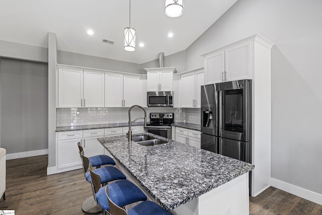 kitchen featuring lofted ceiling, dark wood-type flooring, a kitchen island with sink, and stainless steel appliances