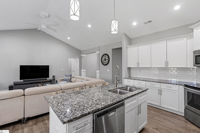 kitchen with a center island with sink, white cabinetry, vaulted ceiling, sink, and stainless steel appliances