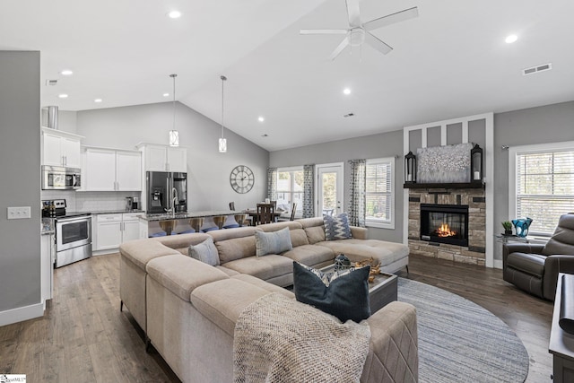 living room with a stone fireplace, hardwood / wood-style flooring, plenty of natural light, and ceiling fan