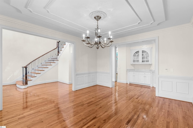 unfurnished dining area with ornamental molding, a chandelier, and light hardwood / wood-style flooring