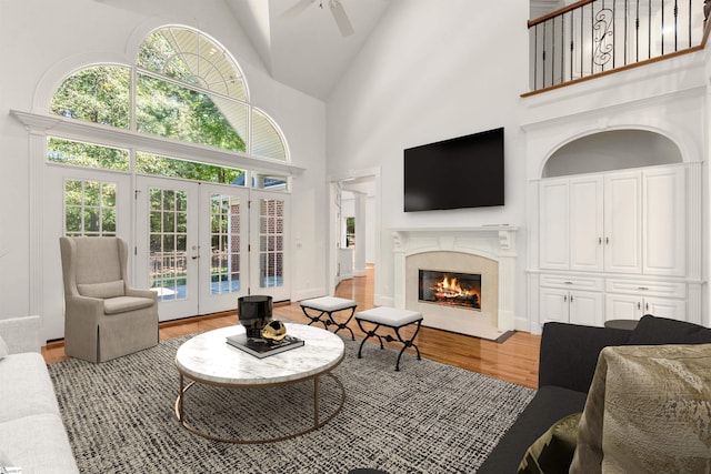 living room featuring hardwood / wood-style floors, french doors, high vaulted ceiling, and ceiling fan