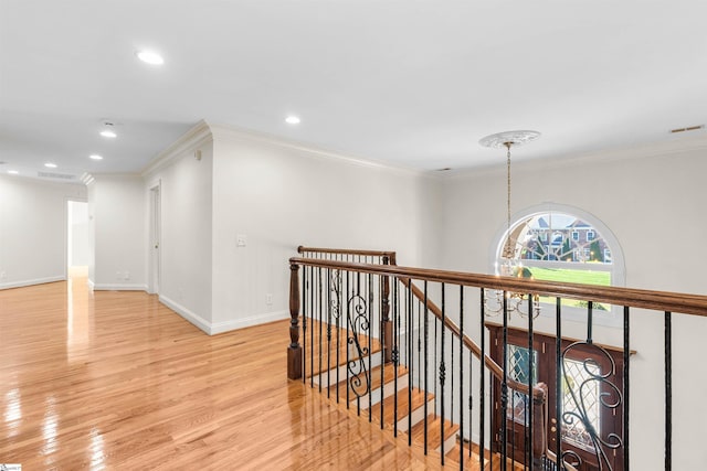 hall with an inviting chandelier, light wood-type flooring, and crown molding