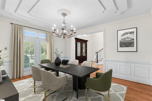 dining space featuring french doors, light hardwood / wood-style floors, crown molding, and a chandelier