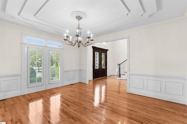 unfurnished dining area with french doors, ornamental molding, a chandelier, and light wood-type flooring