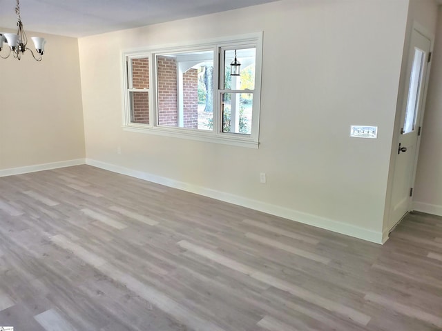 unfurnished room with light wood-type flooring and a chandelier