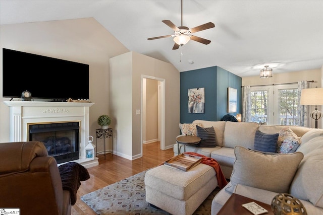 living room featuring light hardwood / wood-style flooring, lofted ceiling, and ceiling fan