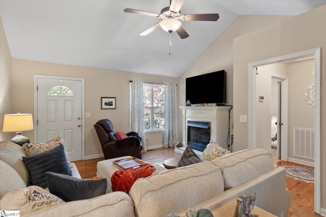 living room featuring light hardwood / wood-style floors, ceiling fan, and vaulted ceiling