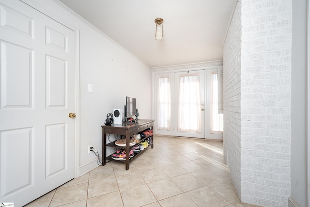 foyer entrance with ornamental molding and light tile patterned floors