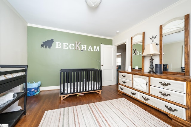 bedroom with crown molding, dark hardwood / wood-style flooring, and a crib