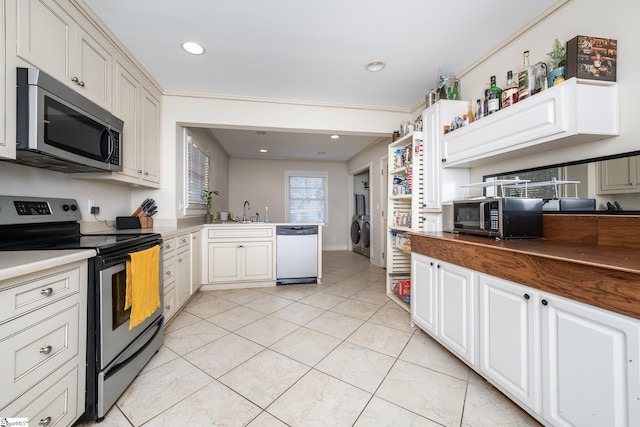 kitchen with washer / clothes dryer, stainless steel appliances, sink, light tile patterned flooring, and white cabinetry