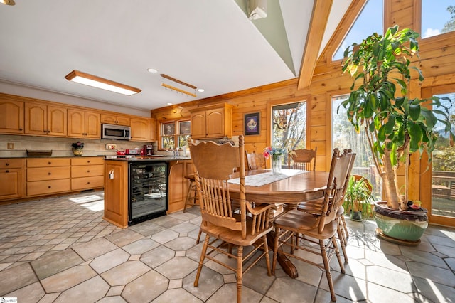 dining room with vaulted ceiling, beverage cooler, and crown molding