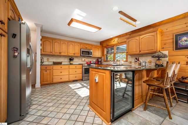 kitchen with kitchen peninsula, stainless steel appliances, crown molding, wine cooler, and a breakfast bar area