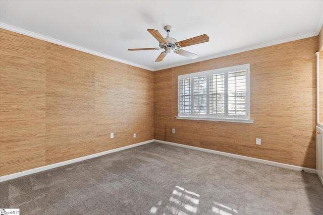 empty room with wood walls, crown molding, carpet floors, and ceiling fan