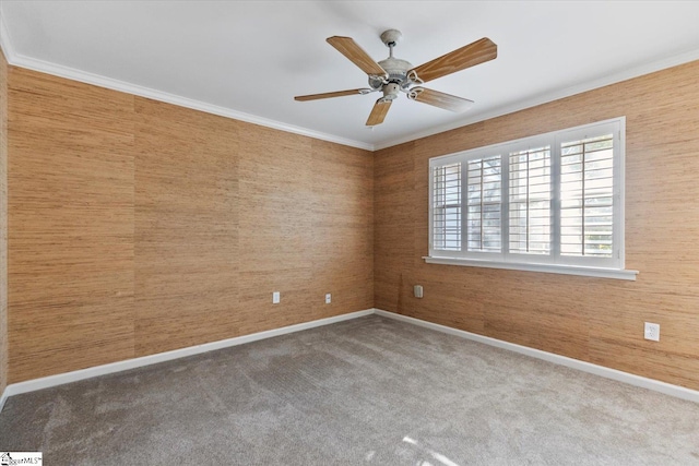 carpeted empty room featuring wooden walls, crown molding, and ceiling fan