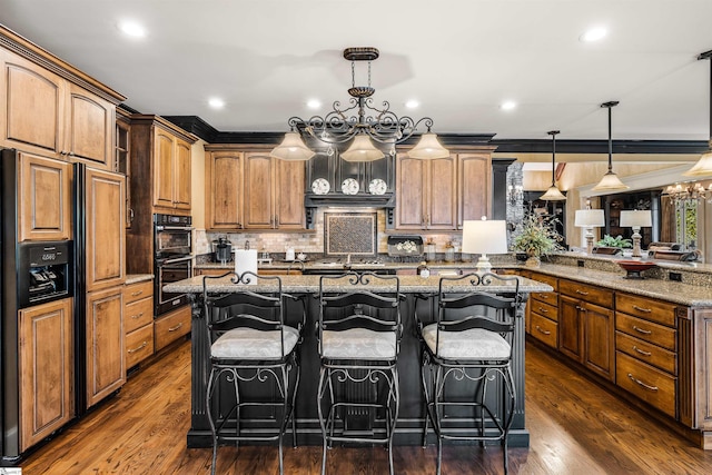 kitchen featuring paneled built in refrigerator, an inviting chandelier, a kitchen bar, and hanging light fixtures