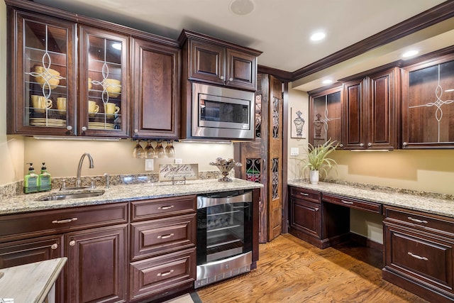 kitchen featuring stainless steel microwave, sink, light stone countertops, beverage cooler, and light hardwood / wood-style floors