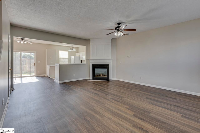 unfurnished living room with ceiling fan, a fireplace, a textured ceiling, and dark hardwood / wood-style flooring