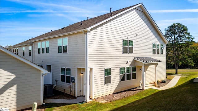 back of house featuring central AC unit and a lawn