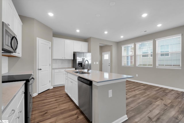 kitchen with white cabinets, an island with sink, hardwood / wood-style flooring, sink, and stainless steel appliances