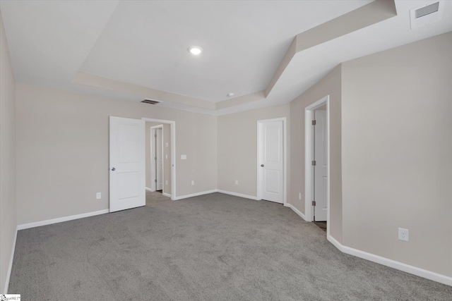 carpeted empty room featuring a tray ceiling