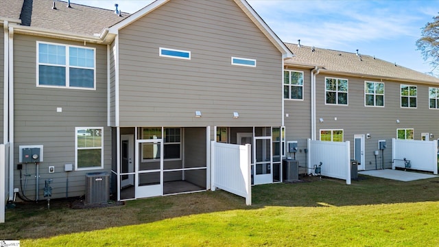 back of house with central air condition unit and a yard