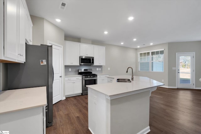 kitchen with white cabinets, an island with sink, appliances with stainless steel finishes, dark wood-type flooring, and sink