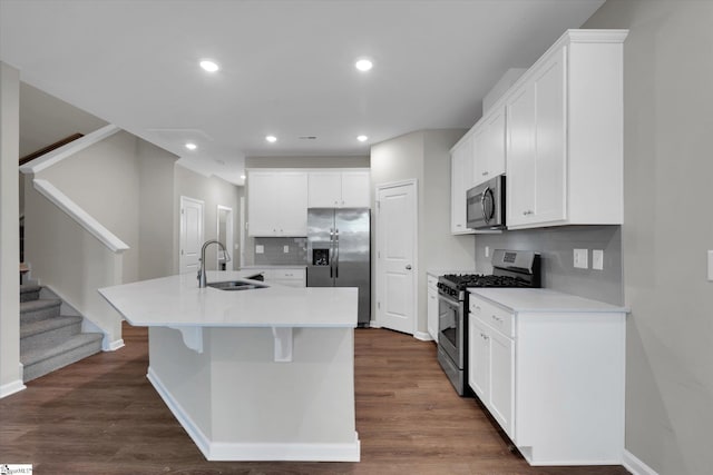 kitchen with sink, stainless steel appliances, white cabinets, dark wood-type flooring, and a kitchen island with sink