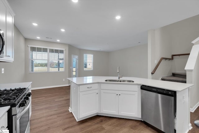 kitchen featuring appliances with stainless steel finishes, sink, white cabinetry, hardwood / wood-style flooring, and a kitchen island with sink