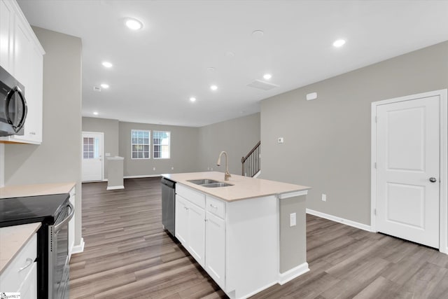 kitchen featuring stainless steel appliances, sink, an island with sink, and white cabinets