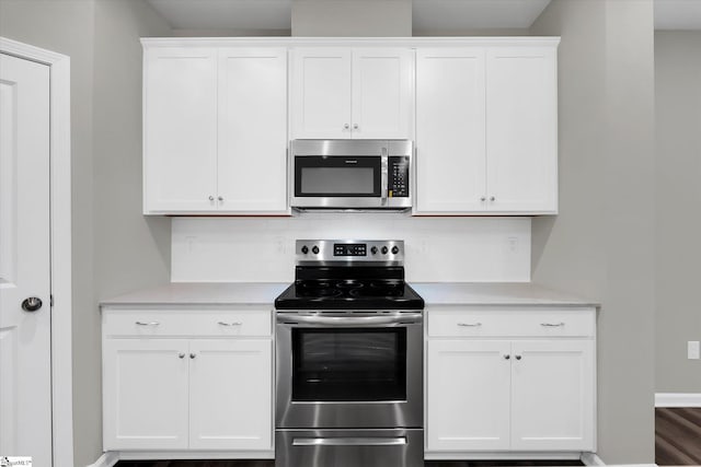 kitchen with hardwood / wood-style floors, appliances with stainless steel finishes, white cabinets, and tasteful backsplash